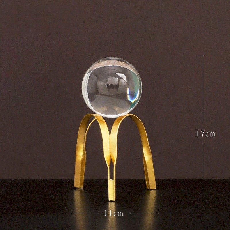 Clear crystal ball on a gold stand with measurements against a dark background