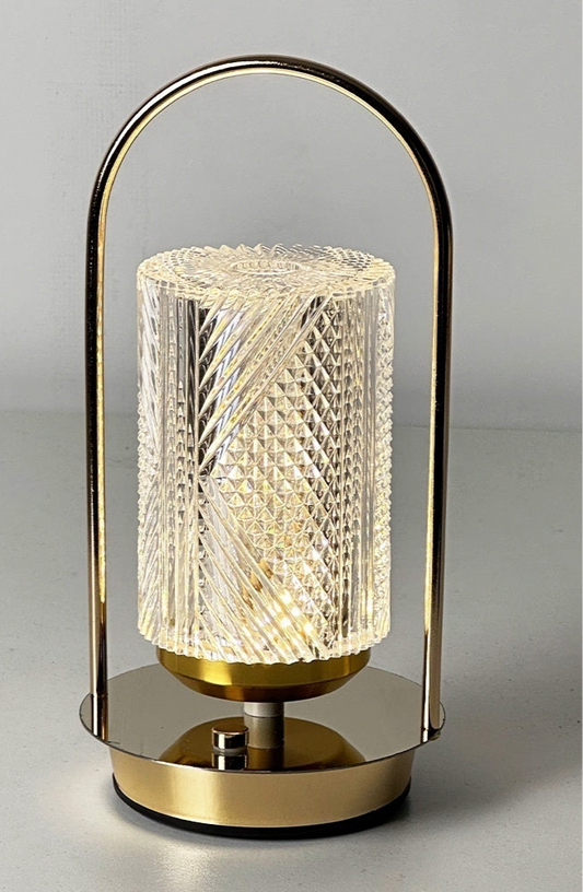 Decorative table lamp with gold base and textured glass shade on a gray background