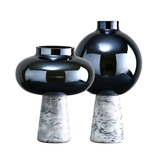 Two black reflective vases with marble bases on a white background