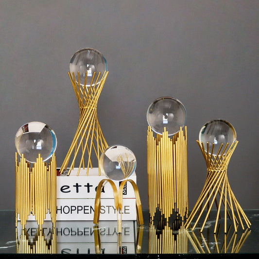 Decorative gold sculptures with clear spherical elements on a dark surface.