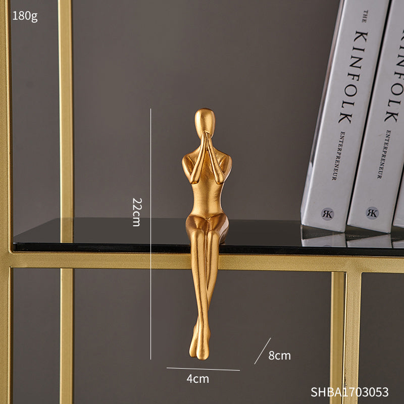 Gold sculpture of a woman on a black surface with measurement details