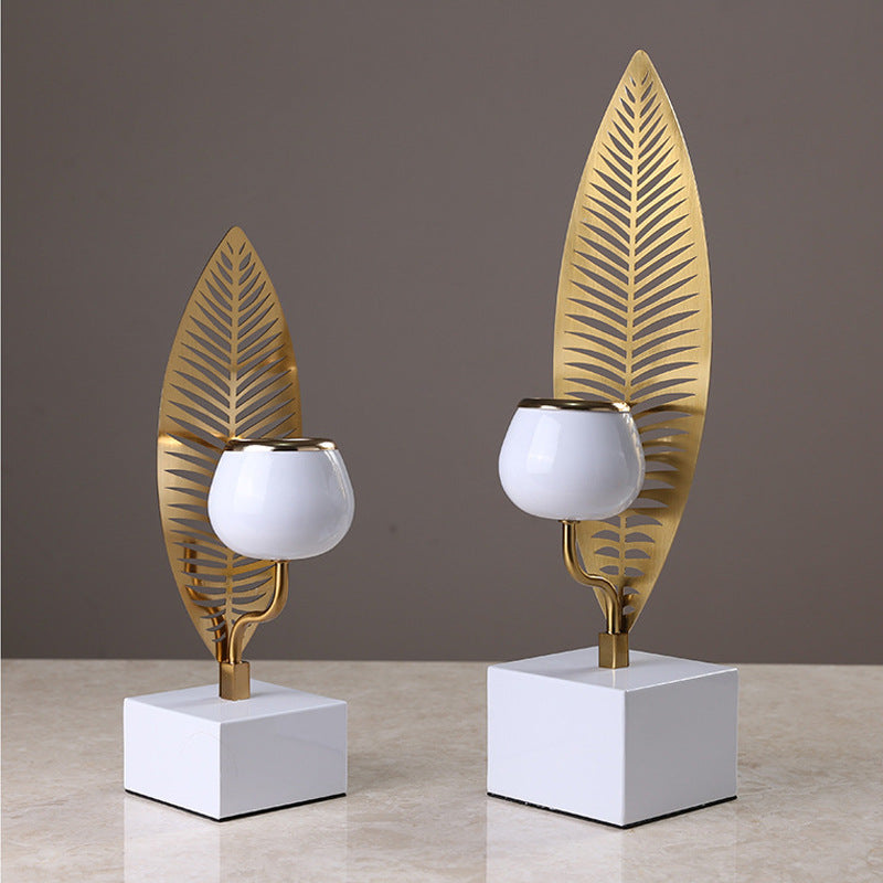 Two decorative candle holders with leaf designs on a neutral background