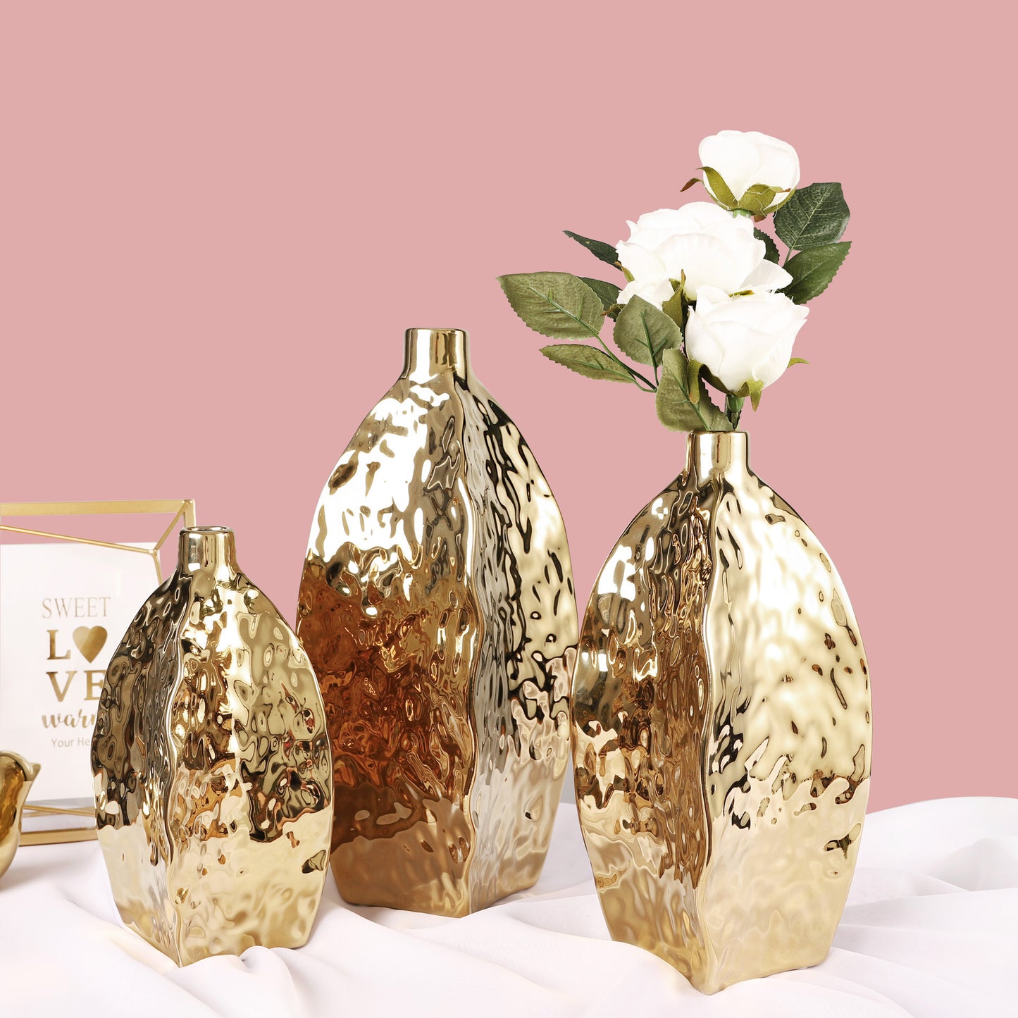 Hammered gold ceramic vase – irregular sculptural shape
Set of three hammered gold vases in S/M/L on table
Modern glam gold ceramic vase with white flowers – DECASA by VS