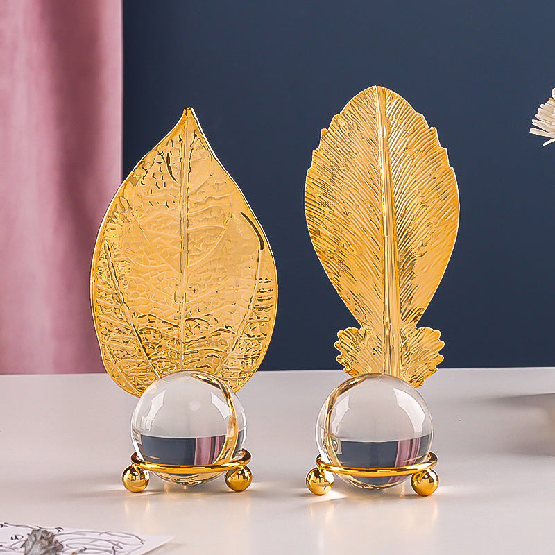 Two decorative items with leaf-shaped gold bases and clear spherical centers on a white surface.
luxury golden sculpture with glass sphere on console table
