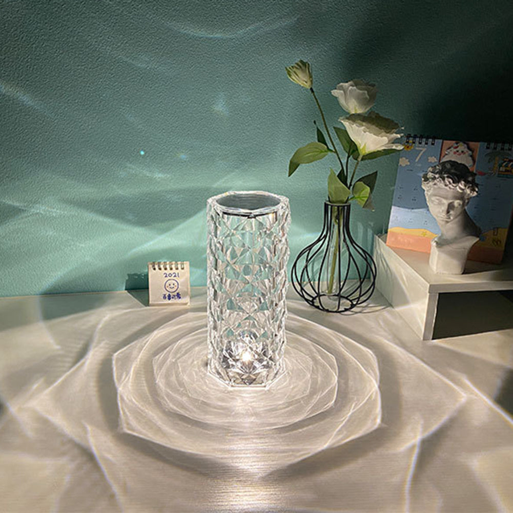 Crystal vase on a textured surface with a calendar and decorative items in the background.