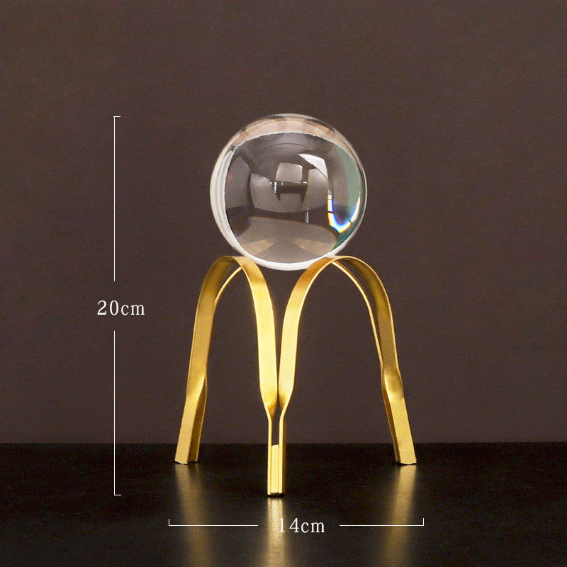 Decorative object with a clear sphere on a gold stand against a dark background