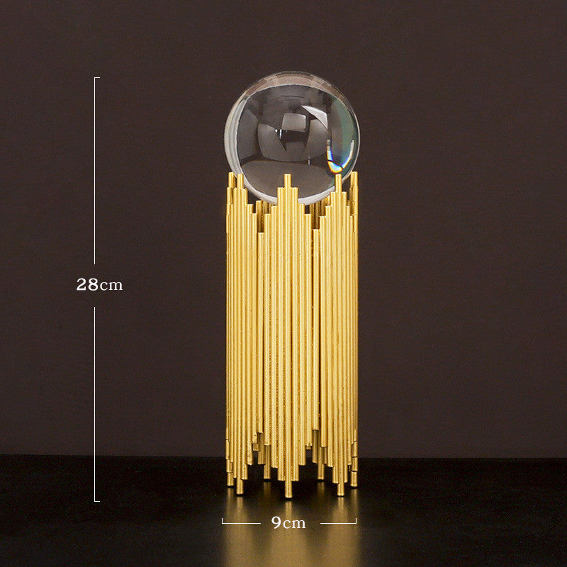 Decorative object with gold cylindrical base and clear sphere on a dark background