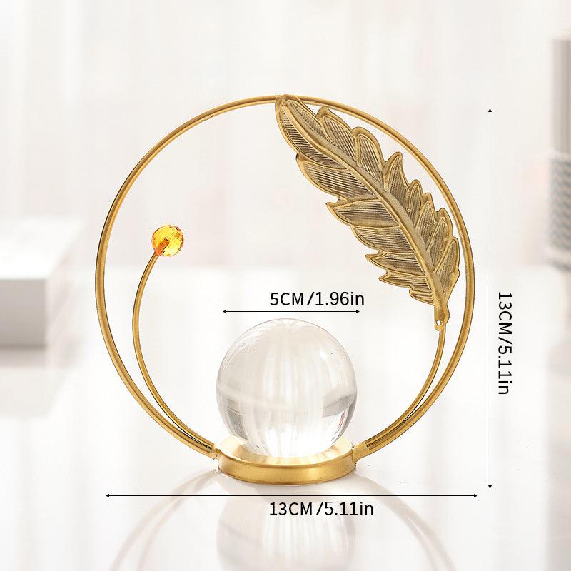 Decorative object with gold feather and crystal ball, featuring measurements on a white background.