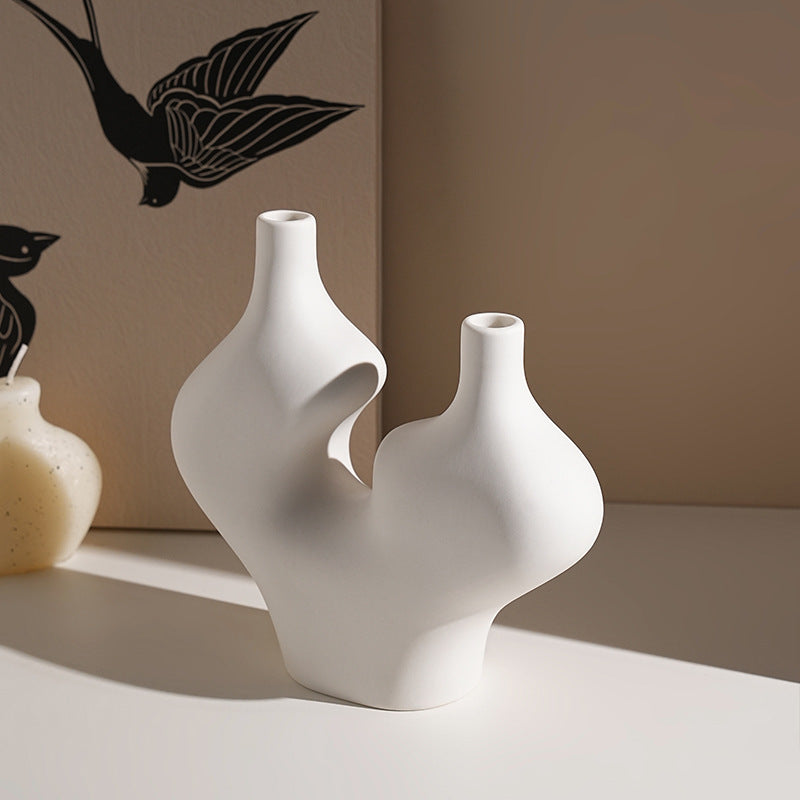 Two white peaks ceramic vase on a light surface with a neutral background