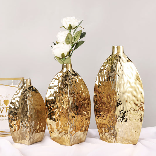 Hammered gold ceramic vase – irregular sculptural shape 
Set of three hammered gold vases in S/M/L on table
Modern glam gold ceramic vase with white flowers – DECASA by VS