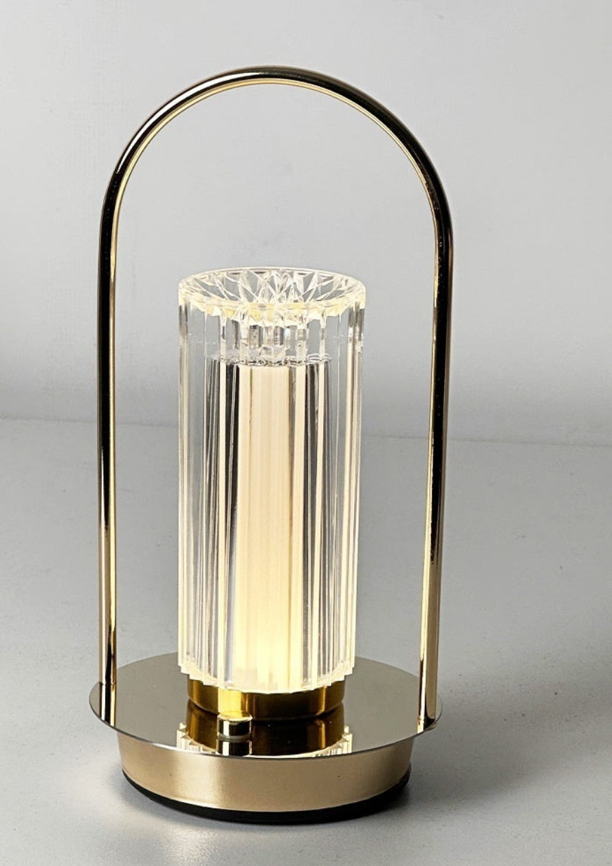 Modern table lamp with gold base and clear glass shade on a light gray background