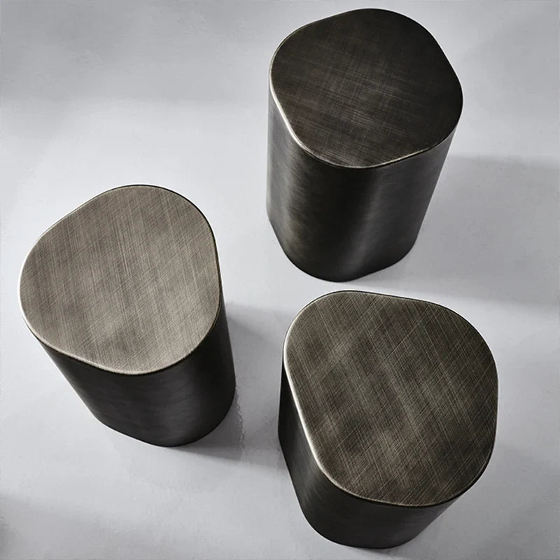 Three metallic stools with a brushed finish on a light gray background